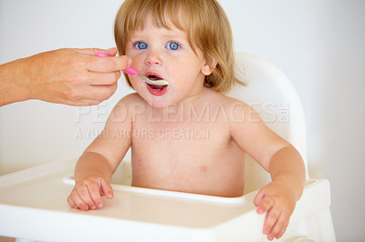 Buy stock photo Hand, baby and eating food or portrait for healthy dinner or childhood development, hungry on spoon. Person, feeding chair and kid face for lunch time or nutrition vitamins, breakfast or parent care