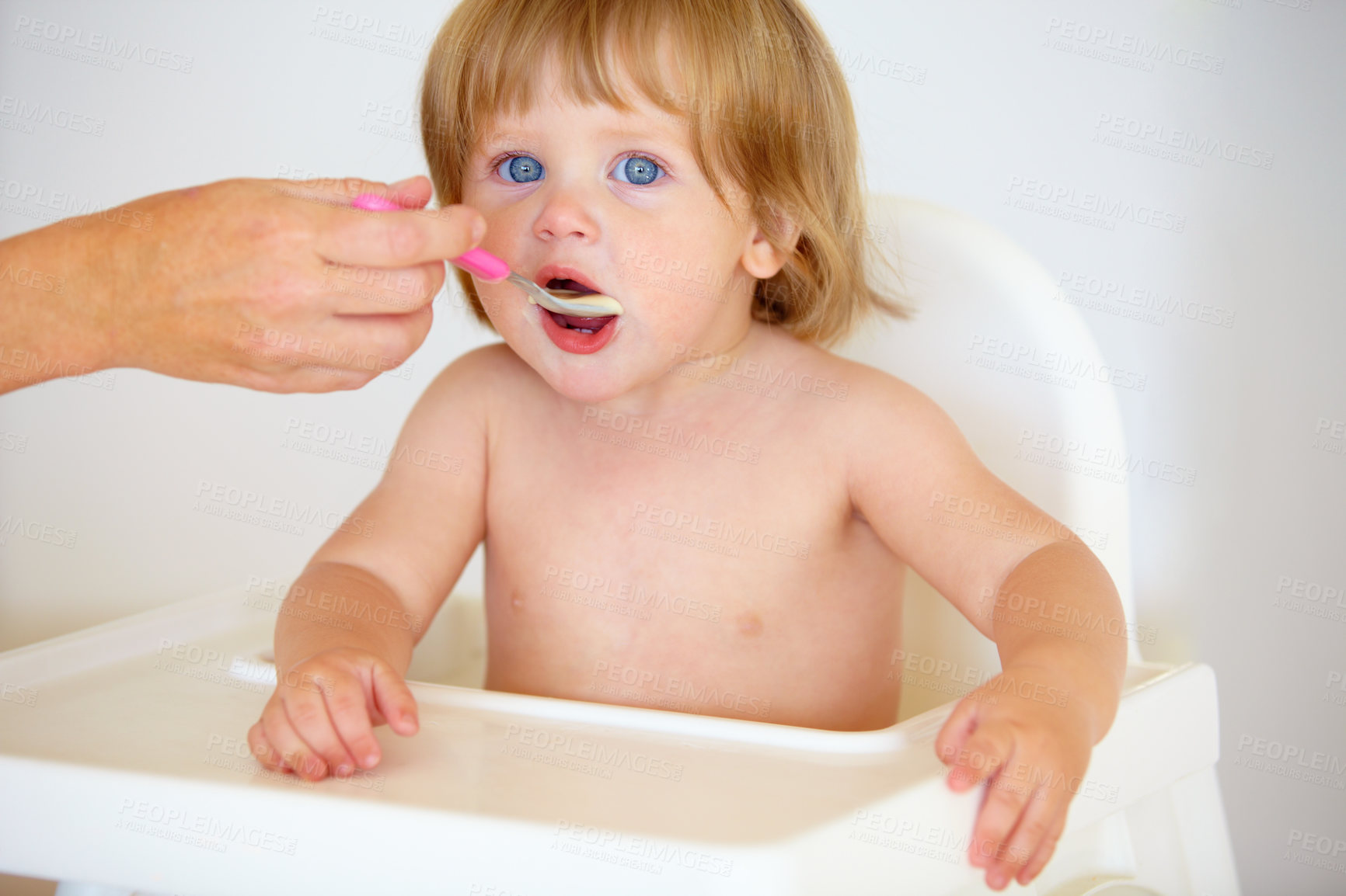 Buy stock photo Hand, baby and eating food or portrait for healthy dinner or childhood development, hungry on spoon. Person, feeding chair and kid face for lunch time or nutrition vitamins, breakfast or parent care