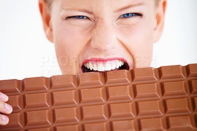 Buy stock photo Crazed young woman biting into a huge piece of chocolate