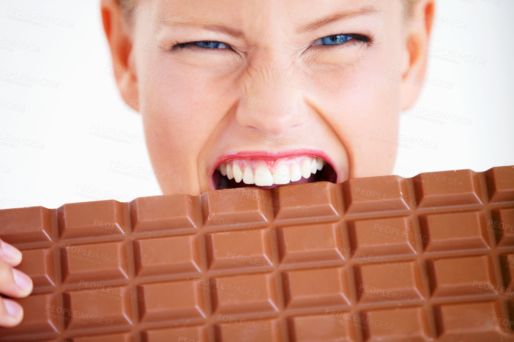 Buy stock photo Crazed young woman biting into a huge piece of chocolate