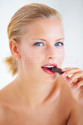 Buy stock photo Beautiful young woman enjoying a delicious piece of chocolate