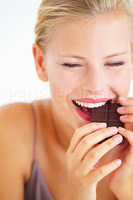 Buy stock photo Young woman enjoying a delicious piece of chocolate with delight