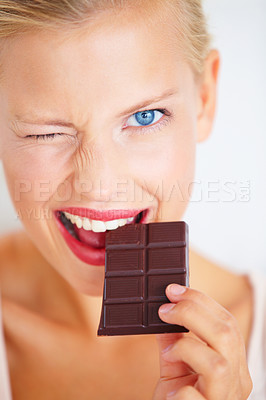 Buy stock photo Portrait, woman wink and eating chocolate bar, delicious snack or candy for studio food, dessert or sugar product. Diet craving, cacao sweets or girl face with cheat meal isolated on white background