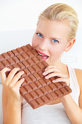 Buy stock photo Young woman biting into a huge bar of chocolate