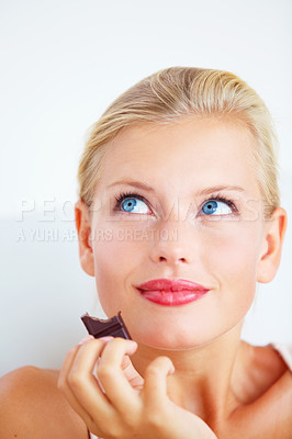 Buy stock photo Smiling young woman enjoying a delicious piece of chocolate