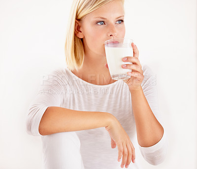 Buy stock photo Thinking, milk and calcium with a woman drinking from a glass in studio isolated on a white background. Diet, nutrition and detox with a healthy young female enjoying a drink for vitamins or minerals