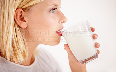 Buy stock photo Profile, milk or nutrition with a woman drinking from a glass in studio isolated on a white background. Health, detox and calcium with a young female enjoying a drink for natural vitamins or minerals