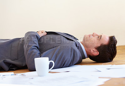 Buy stock photo A handsome young businessman lying on the floor of his office