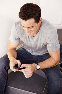 Buy stock photo Man, smile and typing in home with phone, scroll social media post and reading notification on stairs of floor. Happy guy, mobile games and download app, search contact and information on smartphone