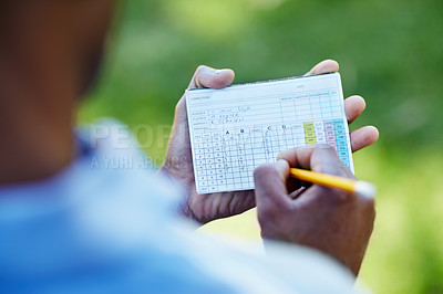 Buy stock photo Rearview shot of a young golfer marking his scorecard