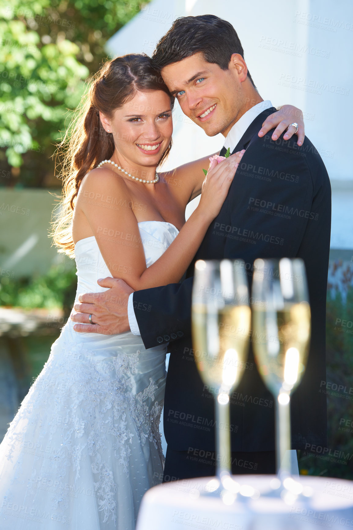 Buy stock photo Happy couple, portrait and hug at wedding with champagne glasses in celebration for love, commitment or marriage. Man hugging woman for embrace, affection or support with alcohol at outdoor ceremony