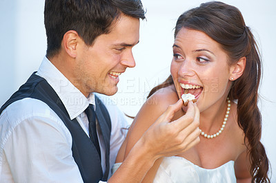 Buy stock photo Fun shot of a young groom feeding his bride wedding cake