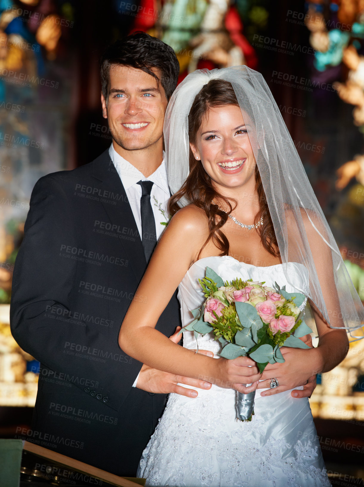 Buy stock photo Portrait of a happy newlywed couple standing in front of stained glass windows