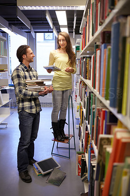 Buy stock photo Shot of a young man and woman choosing books from a bookshelf