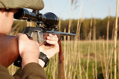 Buy stock photo A game hunter looking through the reeds with his sniper rifle