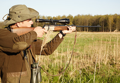 Buy stock photo Hunting, rifle and target with a ranger man aiming a weapon on a field outdoor in nature for sport. Gun, scope and shooting with a male game hunter holding a sniper outside in a grass environment