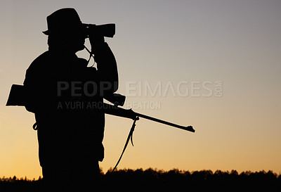 Buy stock photo A silhouette of a game ranger holding his rifle and looking through his binoculars at sun rise in the outdoors