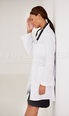 Buy stock photo A stressed out ethnic woman doctor leaning against a wall
