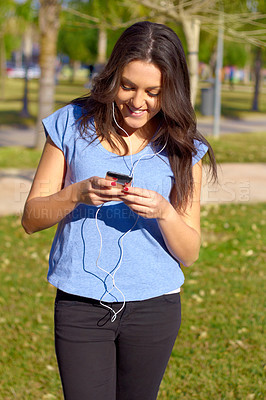 Buy stock photo Shot of an attractive woman listening to music while at the park