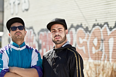 Buy stock photo Two serious men standing in front of a graffiti wall