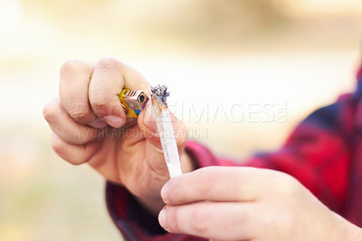 Buy stock photo Shot of a man lighting a large marijuana joint