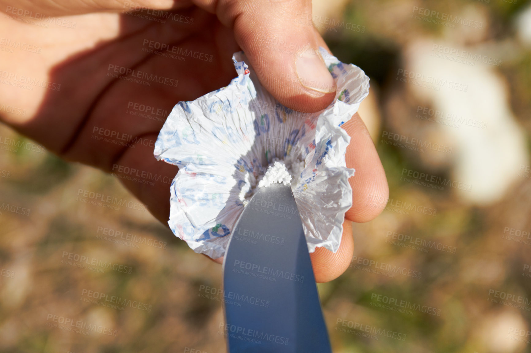Buy stock photo Person, hand and knife with cocaine, drugs or sample for recreation, addiction or habit outdoor. Man, product and packaging on grass in nature with weapon, illegal or unhealthy lifestyle or substance