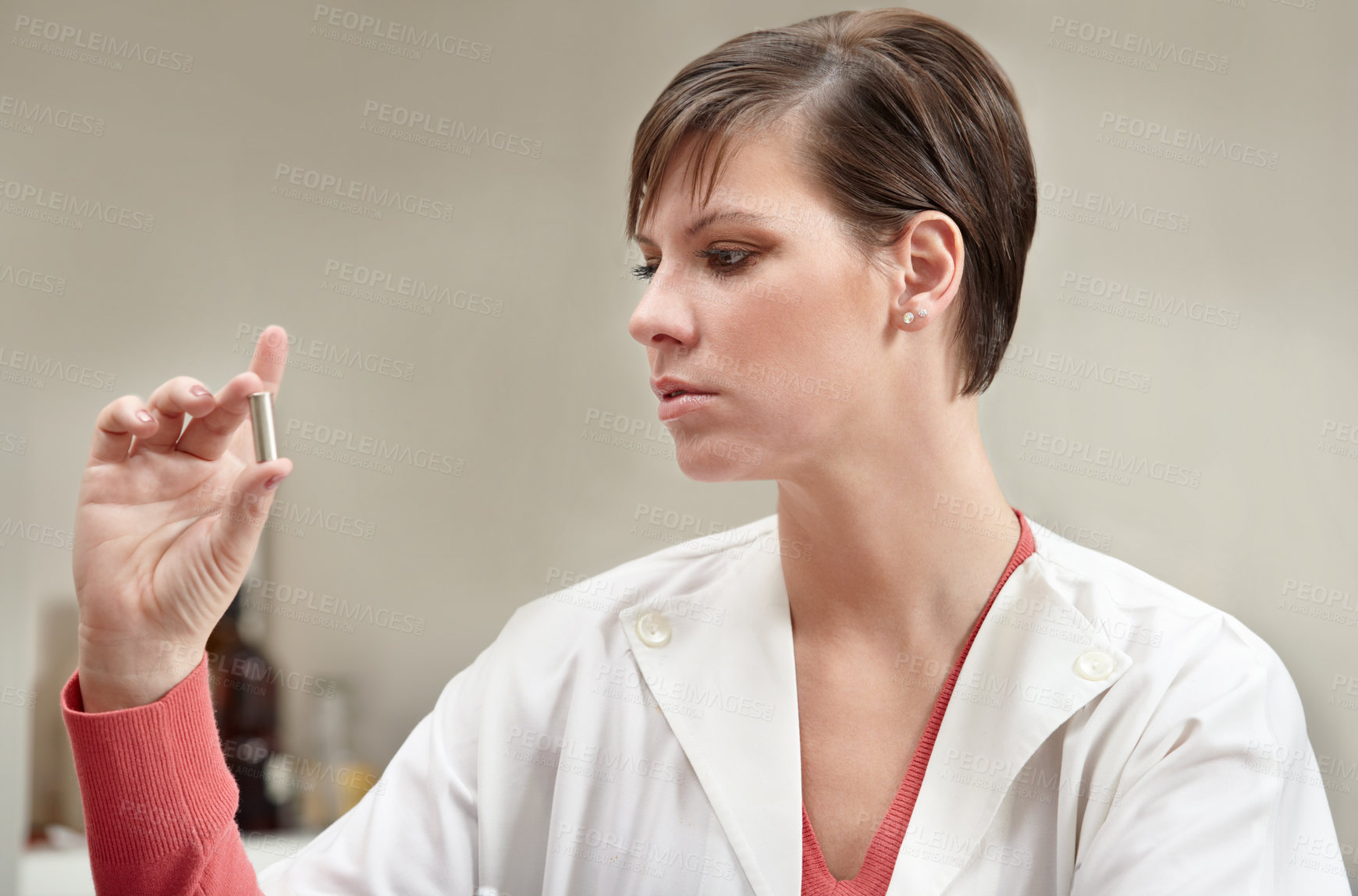 Buy stock photo A forensic technician holding up a bullet and examining it