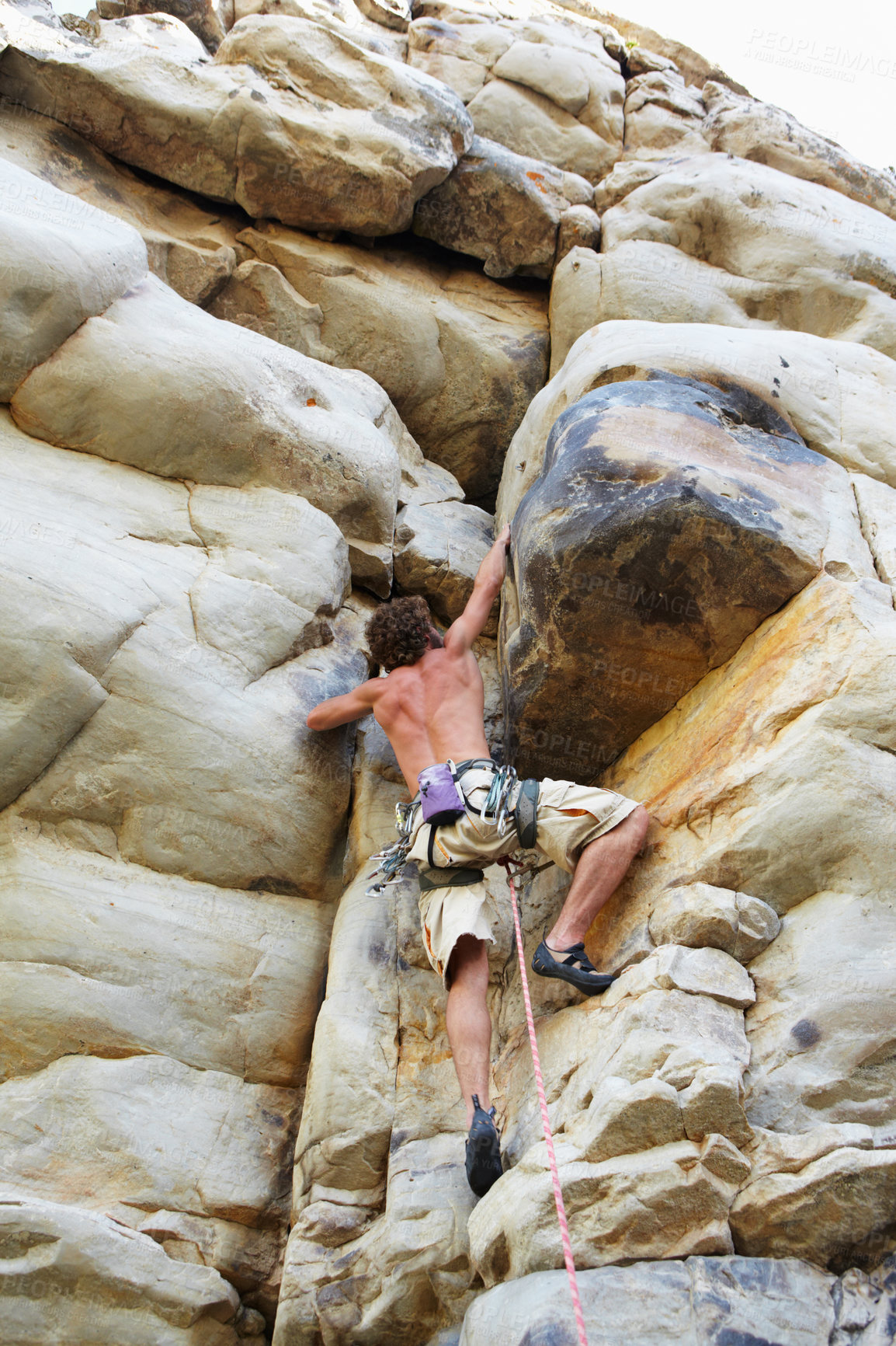 Buy stock photo A rock climber climbing up a cliff face