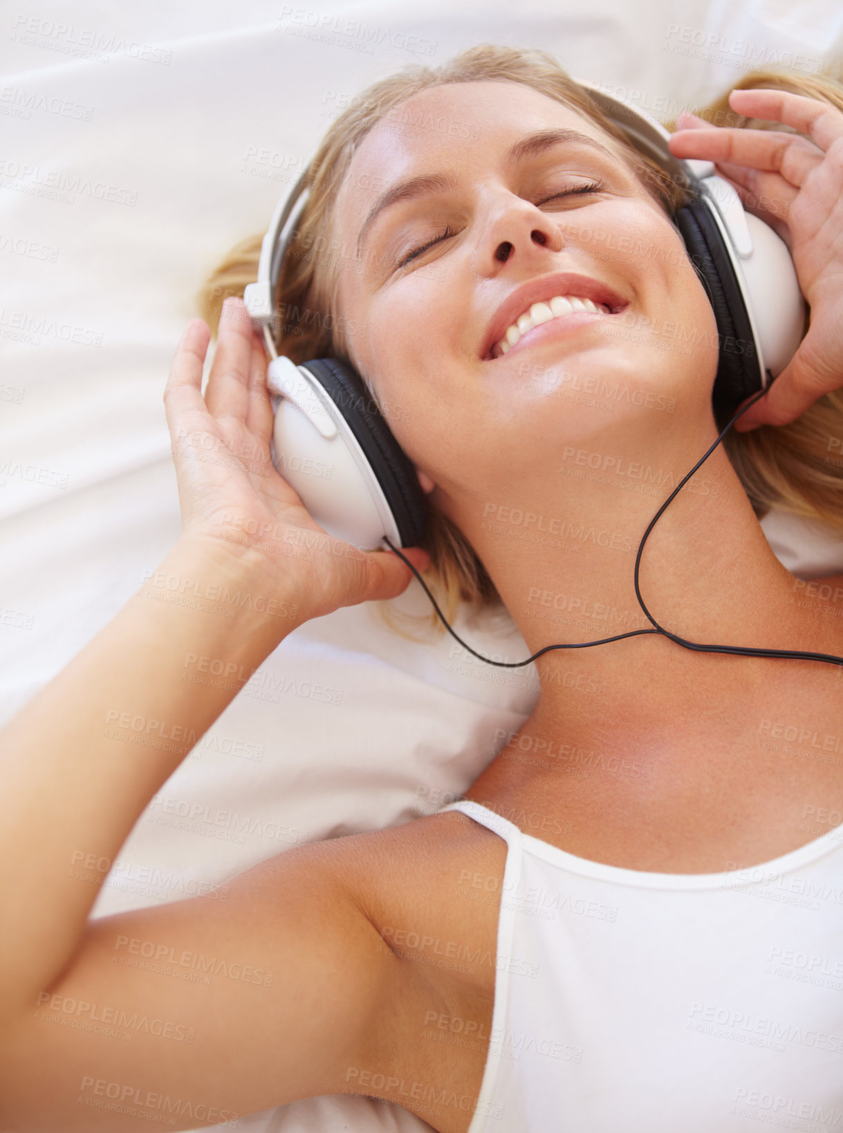 Buy stock photo Woman, eyes closed and smile for listening with headphones in closeup for music, podcast or radio. Person, happy or excited expression for online, streaming service or internet while lying on bed