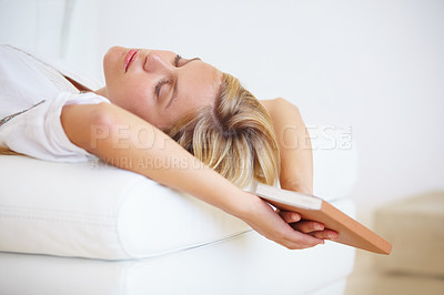 Buy stock photo An attractive young woman falling asleep on the couch with a book in hand