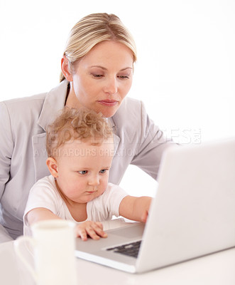 Buy stock photo A businesswoman working on her laptop with her baby on her lap