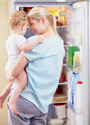 Buy stock photo A mother standing in front of the fridge and holding her baby in her arms