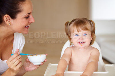 Buy stock photo Portrait, family and a mother feeding her baby breakfast in the morning while in a home together for development. Children, food and a girl toddler eating with a woman parent in an apartment kitchen