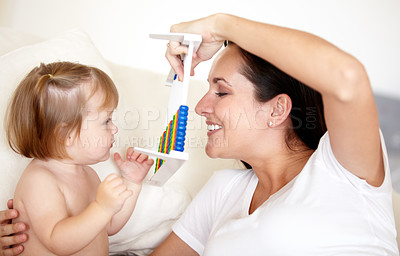 Buy stock photo A young mother holding an abacus up to her little daughter