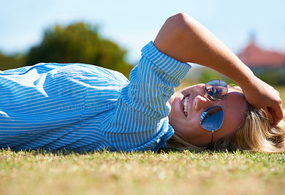 Buy stock photo A happy woman lying on a patch of grass in the sunshine