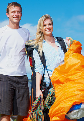 Buy stock photo Couple, parachute or people in nature for sport, smile or paragliding equipment for exercise for wellness. Man, woman or training gear for outdoor fitness, adventure or safety harness in countryside