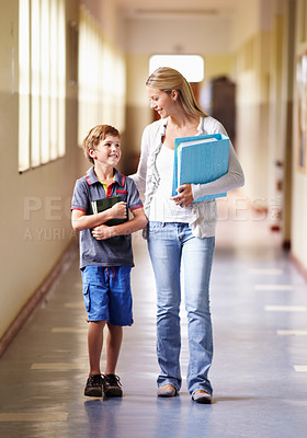 Buy stock photo Teacher, child and walking in corridor at school, talking and bonding together. Education, smile and woman walk with kid, boy or student in hallway while going to class, speaking and discussion.
