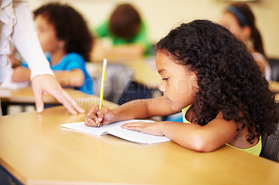 Buy stock photo A cute little girl smiling as she does her homework in class