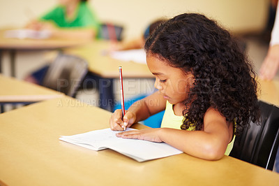 Buy stock photo Education, learning and girl in a classroom, writing and focus with notes, book and homework. Female child, student and kid with development, growth and knowledge for the future, creative and exams