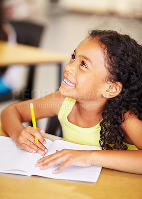 Buy stock photo Happy, school and child writing in her book while listening to a lesson in the classroom. Happiness, smile and young girl kid student doing an education activity, studying or homework by her desk.