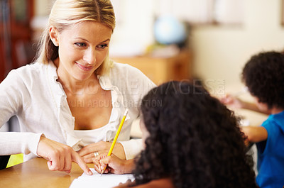 Buy stock photo A young teacher helping children with their work