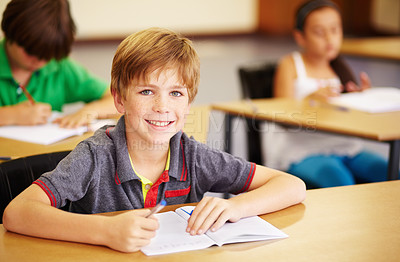Buy stock photo Portrait, education and learning with a student boy sitting by his desk in a classroom for child development. School, kids and writing with a happy young male child in class to study using a notebook