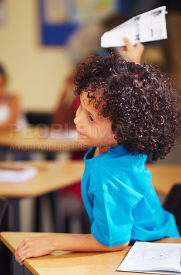 Buy stock photo School, education and paper airplane with a student boy playing in class while sitting at his desk. Classroom, study and learning with an adhd pupil feeling bored while studying for child development