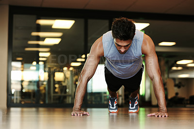 Buy stock photo A handsome man wearing sports clothing doing pushups in the gym