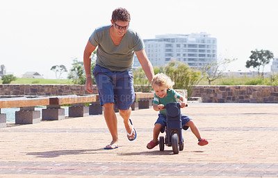 Buy stock photo Happy, running and motorbike with child and father playing in park for bonding, laugh and helping. Smile, happiness and energy with man and young boy riding on scooter for playful, learning or summer