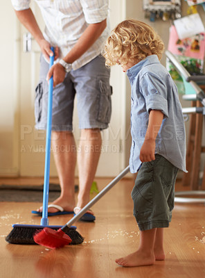 Buy stock photo A father and toddler son sweeping up sand together in their home