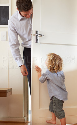 Buy stock photo A little boy playfully push a door closed while his father stands on the other side