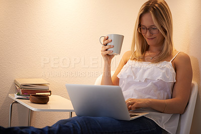 Buy stock photo Happy woman, laptop and journalist with coffee in relax on chair reading, typing or writing in living room at home. Female person or freelancer smile on computer with tea cup in remote work at house