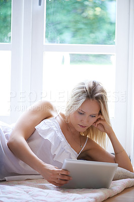 Buy stock photo Woman, tablet and relax on living room floor for online streaming, entertainment or movie at home. Calm female person or blonde lying with technology for reading, series or ebook in lounge at house 
