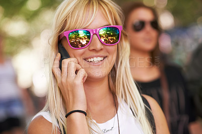 Buy stock photo Shot of a young woman talking on a cellphone at an outdoor festival 